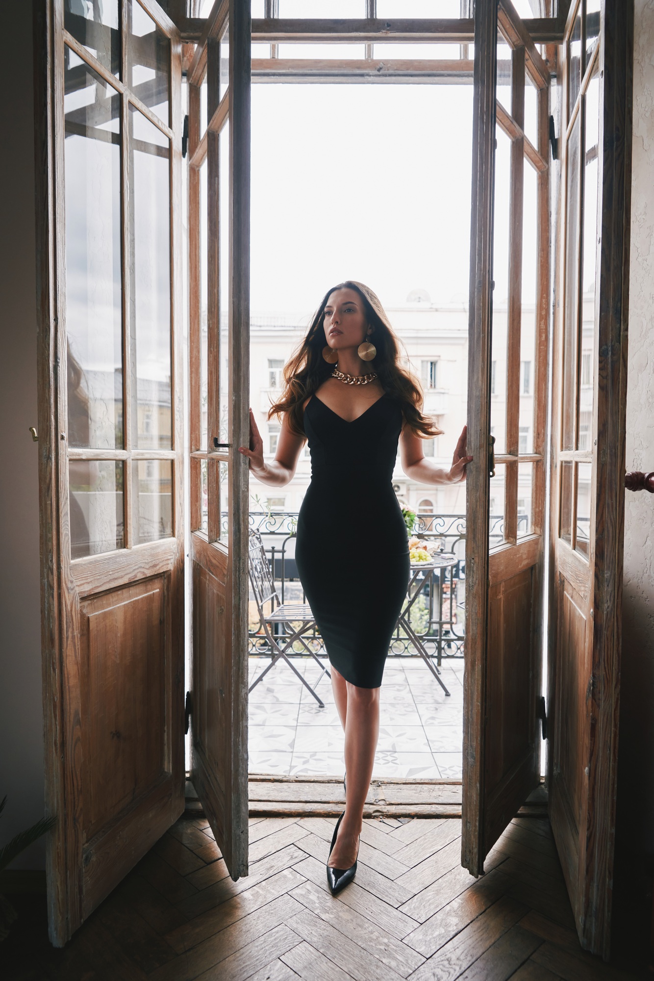 Attractive young woman in cocktail dress opening the doors and coming into the room